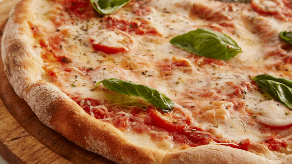 pizza, jossa basilikan lehtiä, juustoa ja tomaattikastiketta