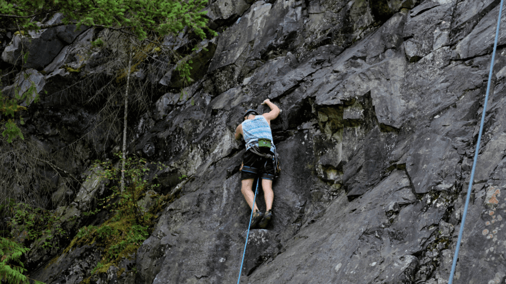 mies kiipeää kallioseinää pitkin ylöspäin