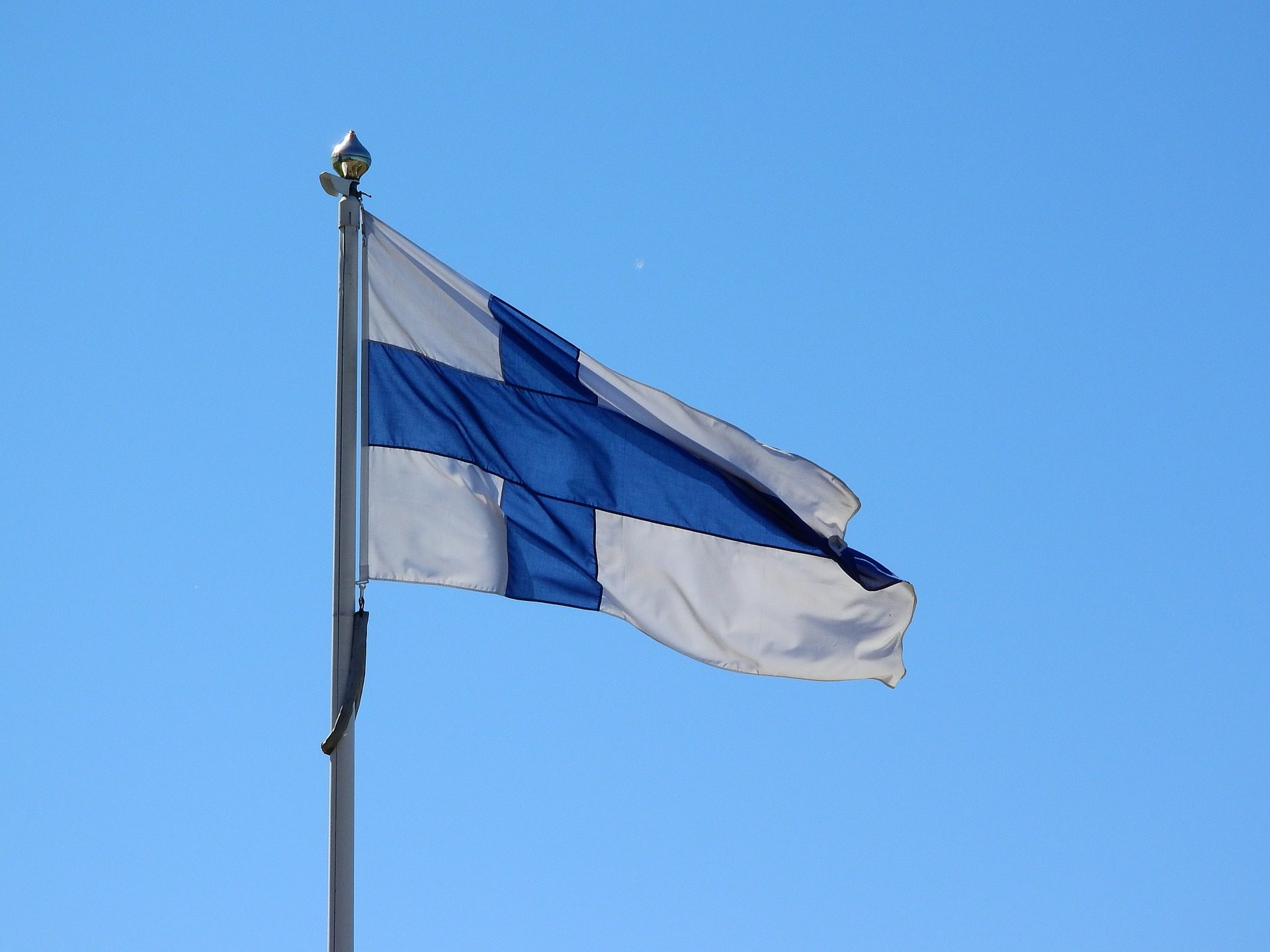 Suomen sinivalkoinen lippu sinistä taivasta vasten.