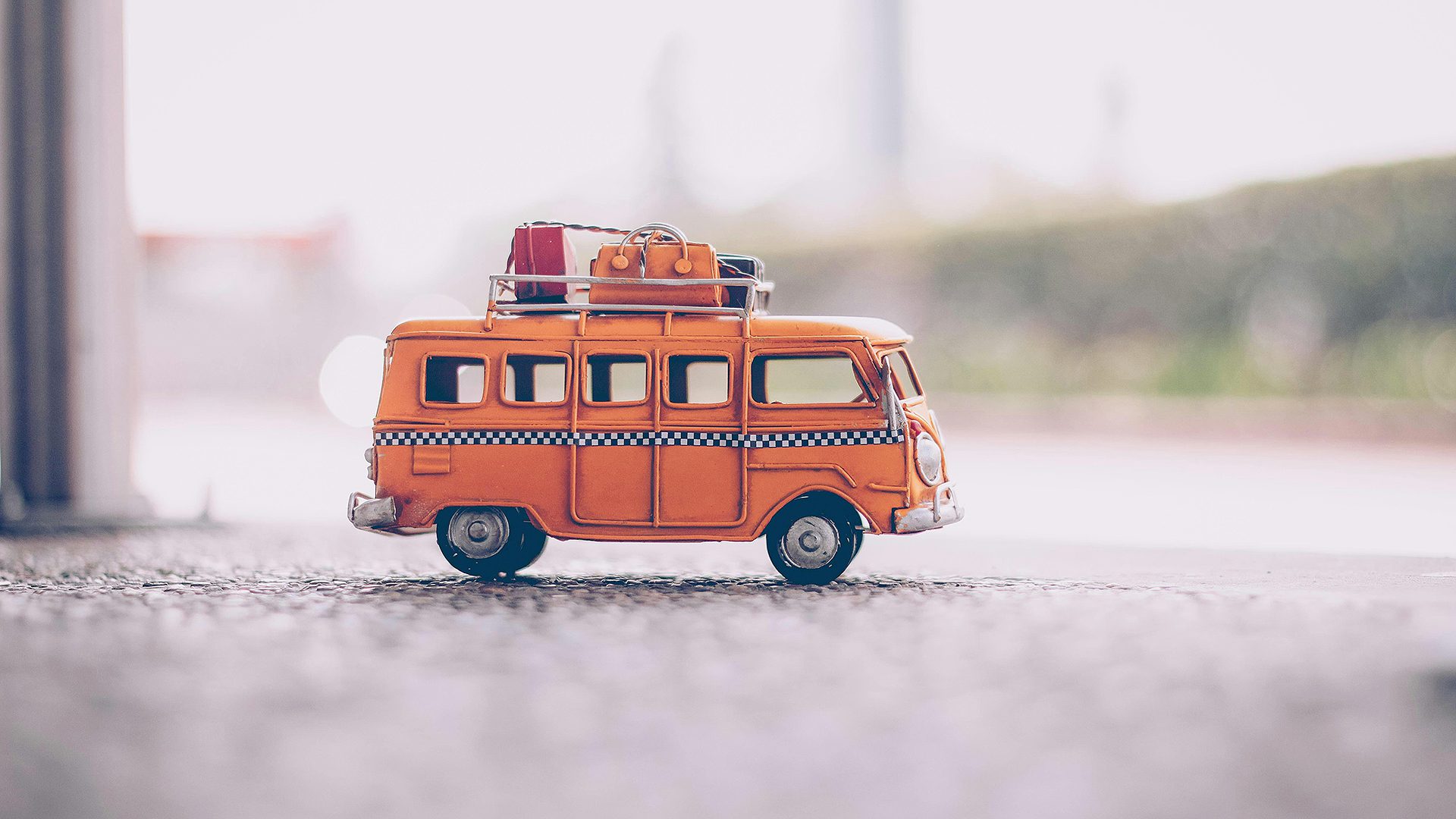 pieni oranssin värinen leikkibussi, jonka katolla matkalaukkuja ja tavaroita
